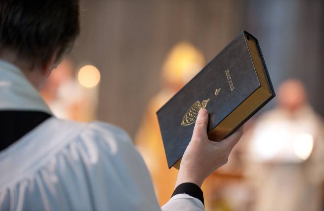 Member of clergy holding bible in the air