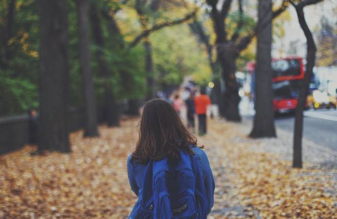 School child walking down street, autumn leaves everywhere