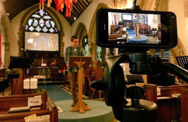 Man at front of church being filmed on phone 