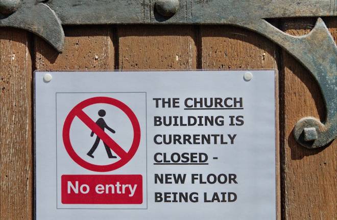 Close up of a sign on a door that says the church is closed while a new floor is being laid
