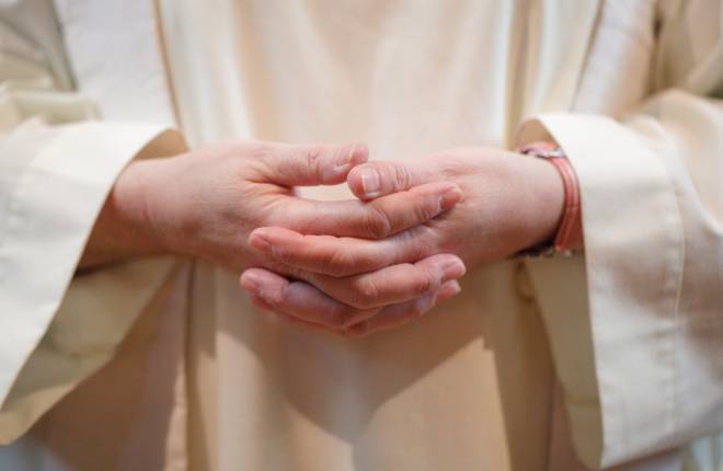 Close up of vicar's clasped hands