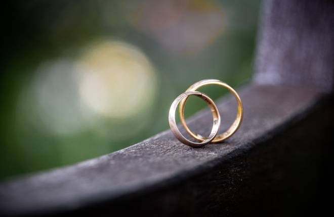Two wedding rings are balanced on a bench.