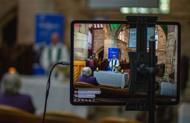 A vicar leading a socially distanced service being live streamed on an iPad.