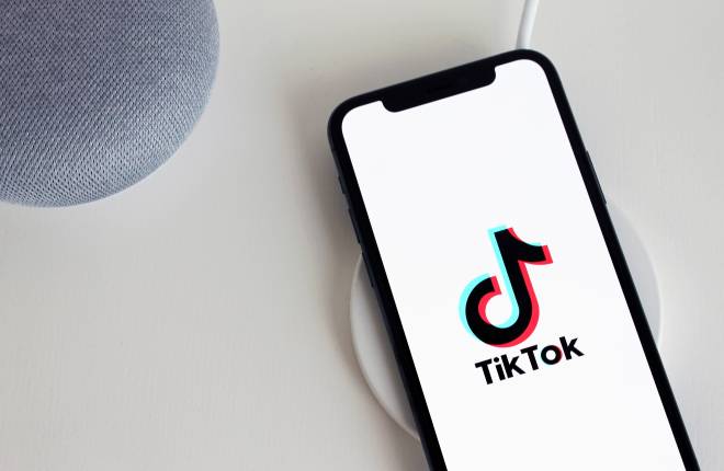 The TikTok logo is shown on a smartphone 