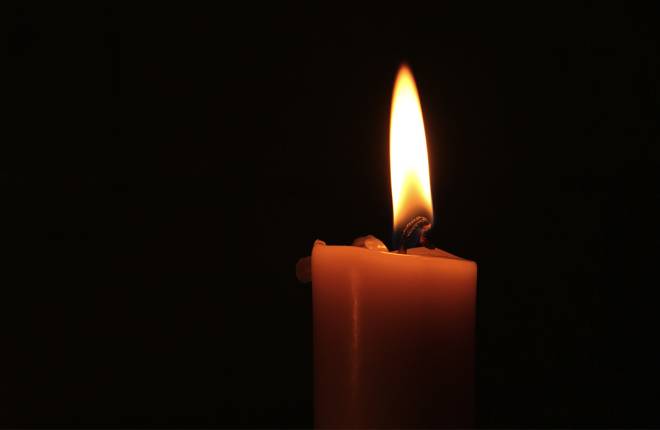 A lit candle burning in the dark.