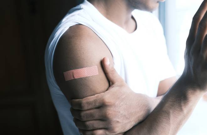 adhesive bandage on young man's arm following covid vaccine jab