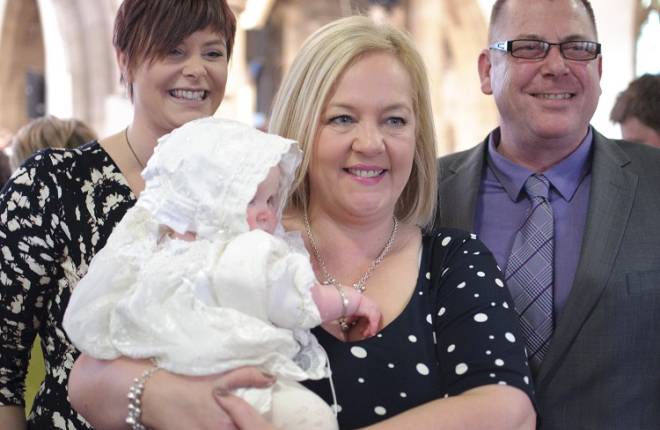 A mum and her baby's godparents at a christening