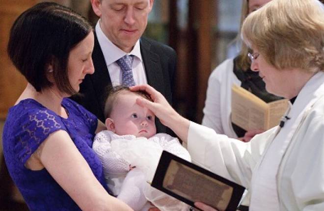 A vicar signing a baby with the cross