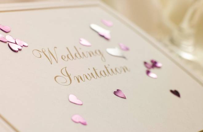A wedding invitation with pink heart confetti on it
