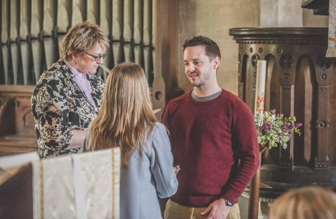 A couple and the vicar at a wedding rehearsal