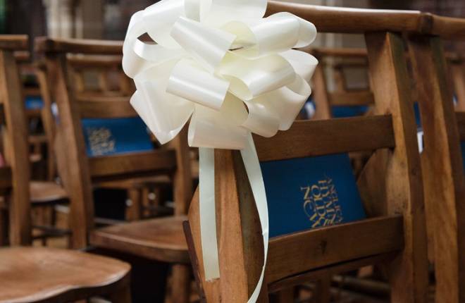 Wedding decorations: a bow tied to a pew end