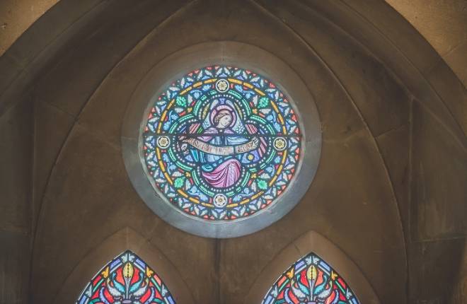 A round stained glass window featuring an angel