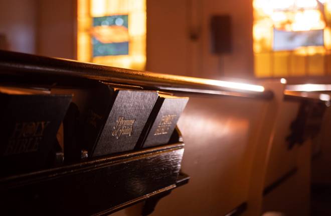 Pews in a local church with a bible and hymn book in the foreground