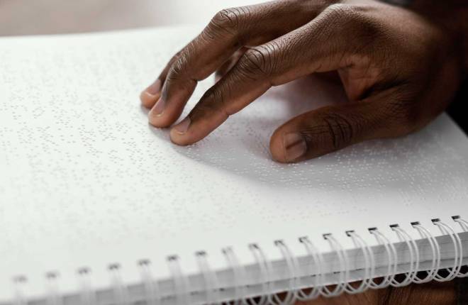 Close up of hand on braille notebook