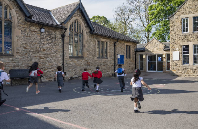 Children run towards a school building