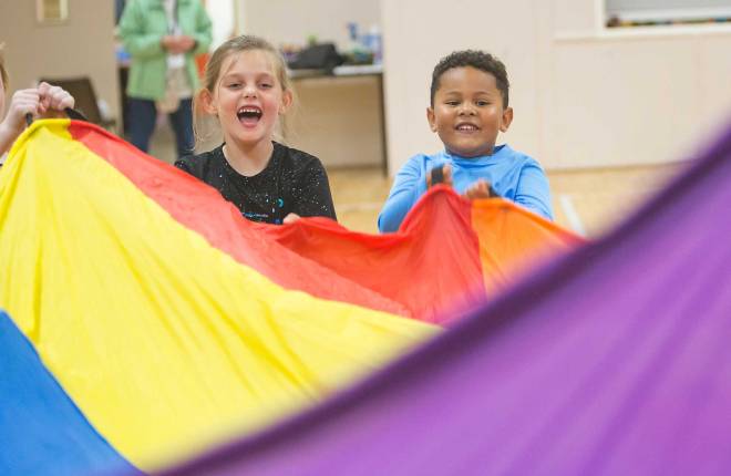 Two children playing with a multicoloured fabric