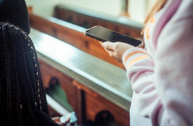 Mobile phone held in someone's hand, with pews in the background